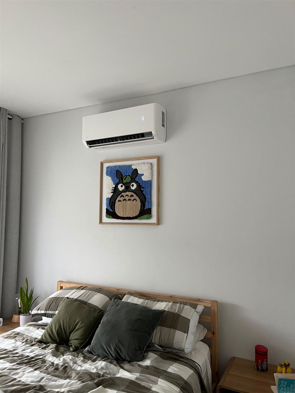 White wall-mounted split system air conditioner installed above a bed