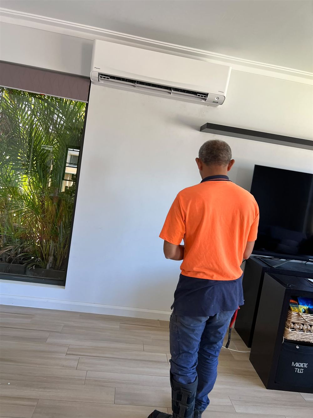 HL AIR technician checking a wall-mounted split system in a living room