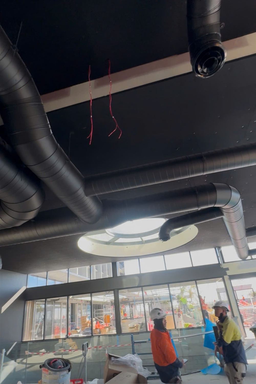 Black spiral ductwork installed across the ceiling of a commercial building under construction